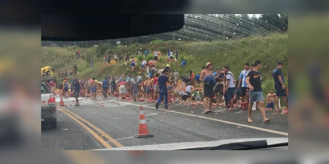 Caminhão carregado com latas de cerveja tomba e população saca a carga